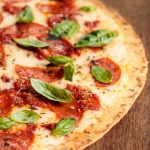 Close up vertical picture of easy thin crust pizza with basil and pepperoni