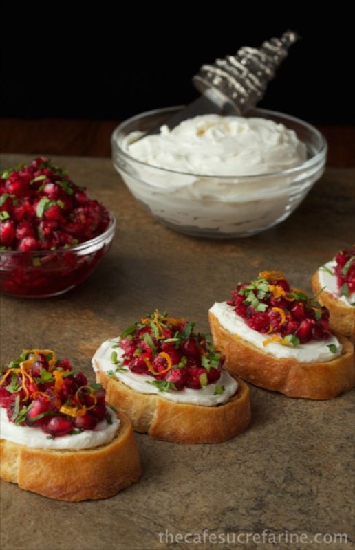 Cranberry and Pomegranate Bruschetta on toasts with goat cheese on a serving platter. Holiday appetizers post.