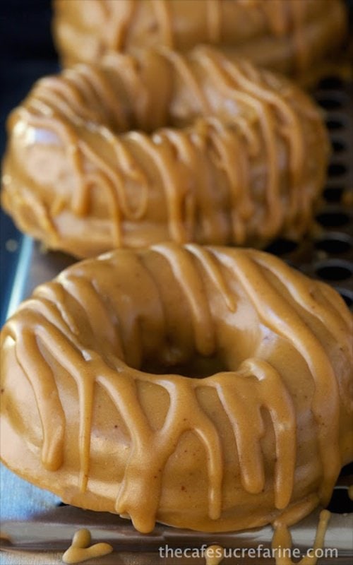 Vertical picture of Baked Pumpkin Buttermilk Donuts on a cooling rack on a black background