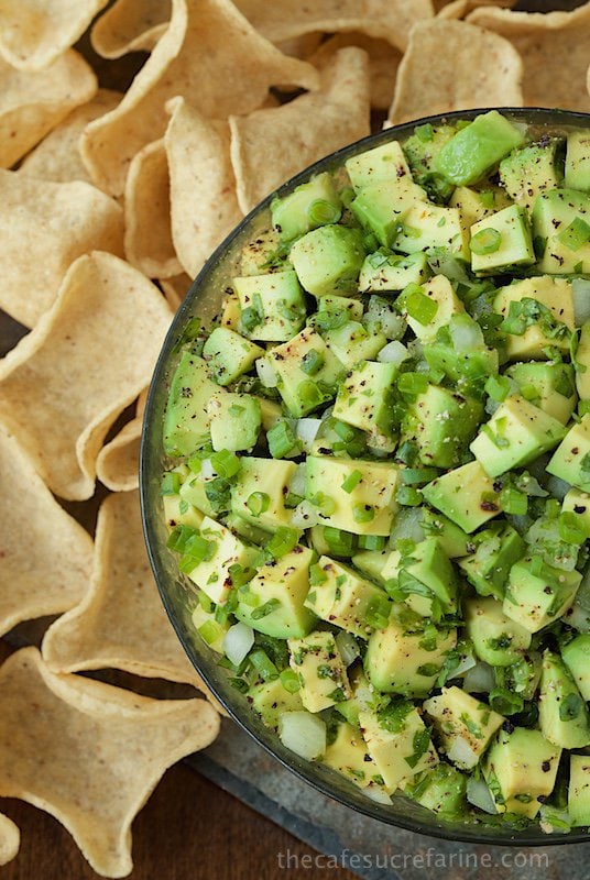 Overhead photo of a glass bowl of Best Avocado Salsa surrounded by tortilla chips.