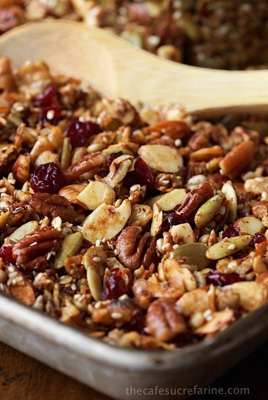 Photo of a cookie pan full of Paleo Granola with a wooden spoon in the middle.