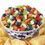Vertical photo of Red, White and Blue Salsa in a blue and white bowl with chips.