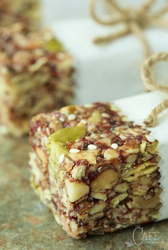 Closeup vertical photo of Dried Cherry and Almond Energy Bars wrapped in decorative paper and twine on a slate surface.