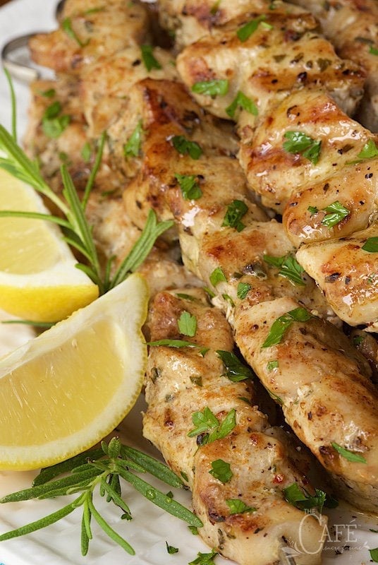Close up photo of Lemon, Rosemary and Garlic Chicken Skewers with lemon wedges and rosemary as a garnish.