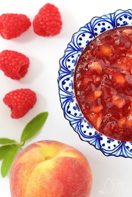 It takes just thirty minutes to throw together a batch of this yummy Peach Raspberry Freezer Jam! It's really easy and you'll be thanking yourself over and over, when the cold winds blow! www.thecafesucrefarine.com