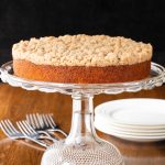 Vertical photo of an Easy Overnight Coffee Cake on a glass pedestal plate on a wood table.