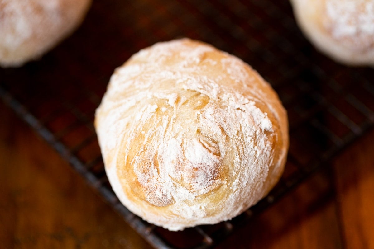 Horizontal extreme closeup photo of a Ridiculously Easy Artisan Roll on a black cooling rack.