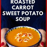 Vertical closeup photo of a person holding a bowl of Thai Roasted Carrot and Sweet Potato Soup.