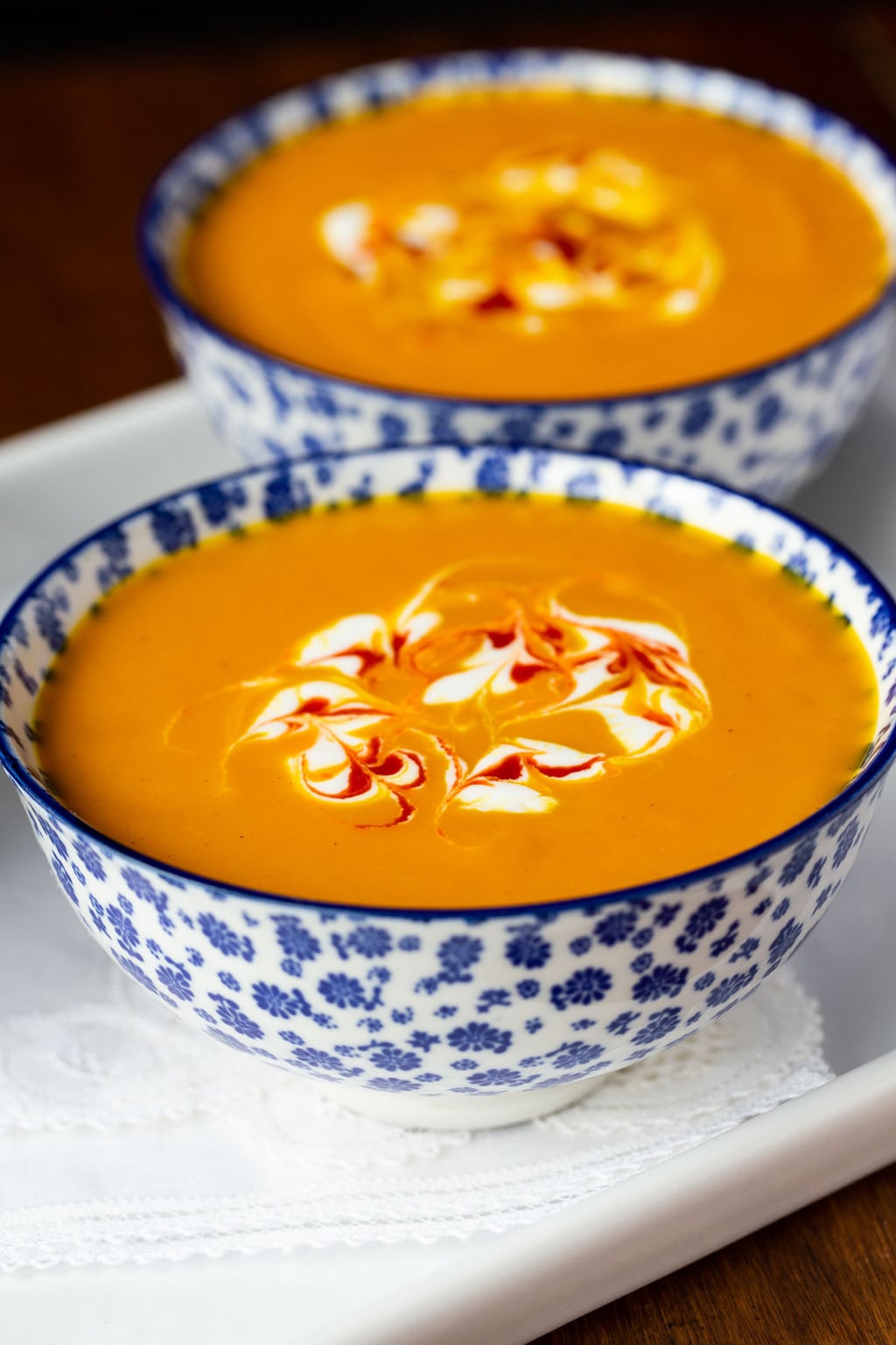 Vertical closeup photo of Thai and Carrot Sweet Potato Soup in a blue and white serving bowls.