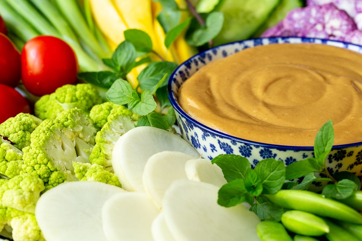Horizontal closeup photo of an appetizer platter of fresh vegetables featuring 5-Minute Easy Peanut Sauce.
