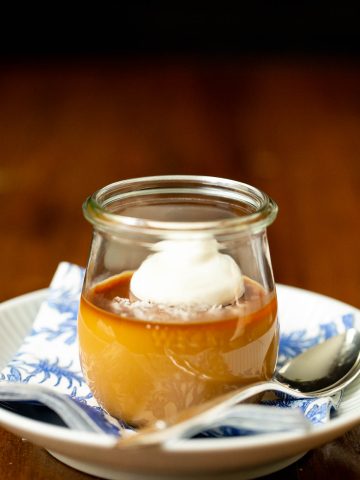 Vertical picture of Butterscotch Pots de Crème in a glass jar on a blue and white plate