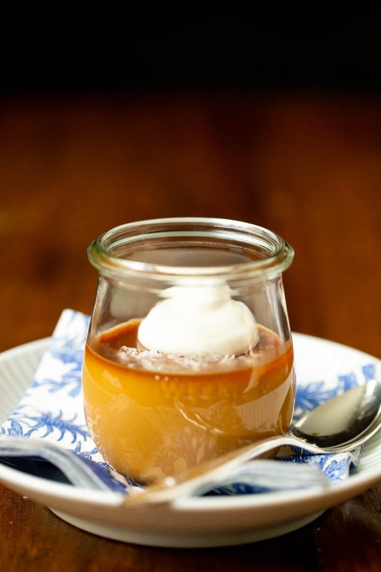 Vertical picture of Butterscotch Pots de Crème in a glass jar on a blue and white plate