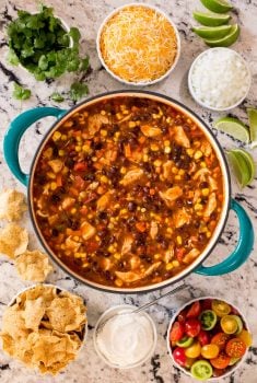 Overhead picture of Chicken Black Bean Chili in a dutch oven with small bowls of toppings