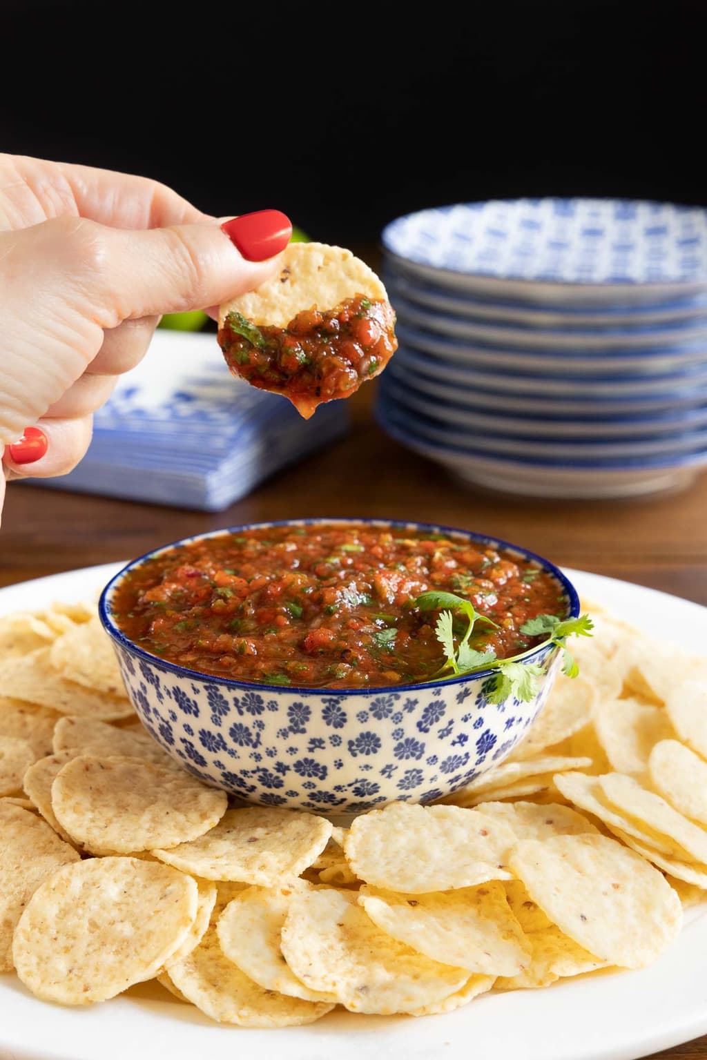 Vertical photo of Best Ever, Super Easy Salsa in a blue and white bowl surrounded by tortilla chips.