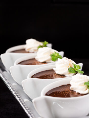 Vertical picture of Chocolate Pots de Creme in white ramekins with mint and whipped cream