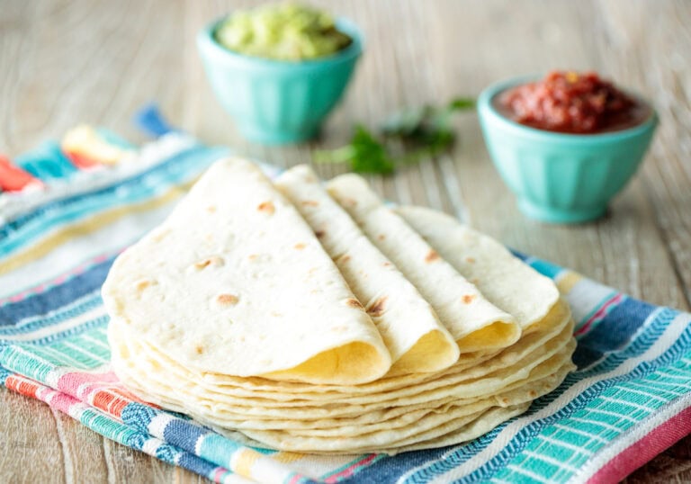 a stack of homemade flour tortillas on a colorful towel background