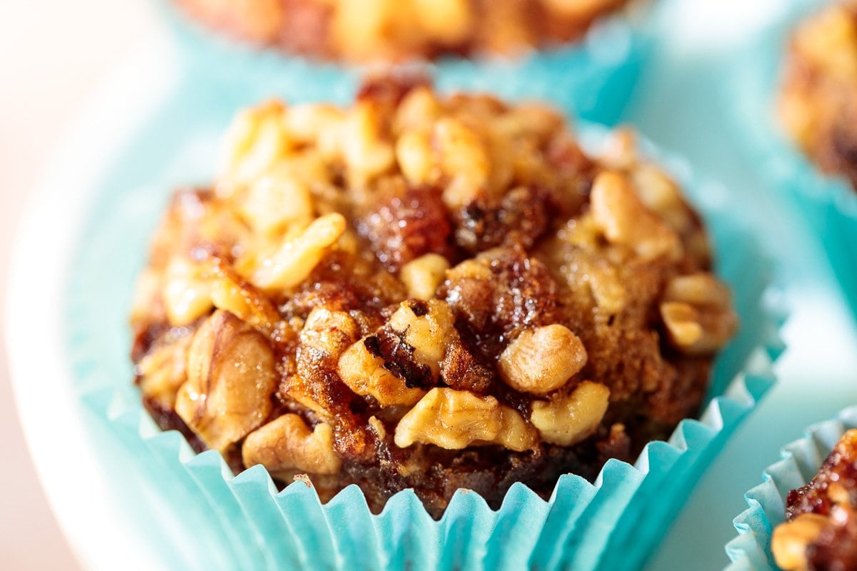 Horizontal extreme closeup photo of a Candied Walnut Date Banana Muffin in a turquoise cupcake liner.