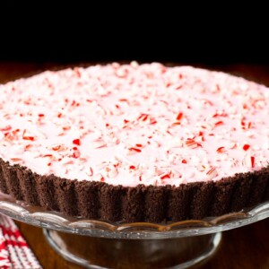 Horizontal closeup photo of a Peppermint Candy Cane Tart on a glass pedestal serving plate.