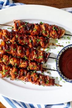 Horizontal overhead photo of Bacon Bourbon Barbecued Chicken Skewers on a white oval serving platter.