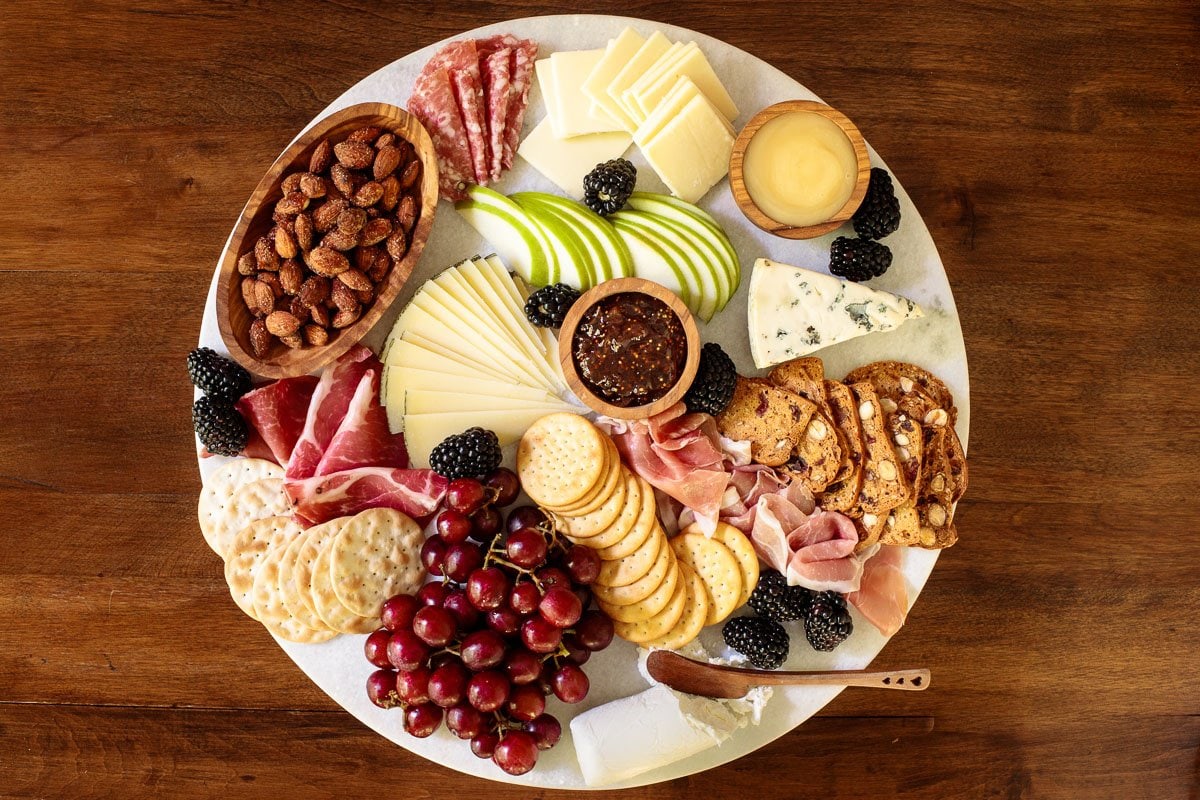 Overhead horizontal photo of a cheese board on a wood table.