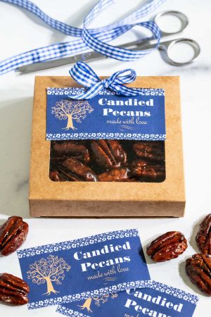 Vertical photo of a gift box of Easy Candied Pecans decorated with blue and white checkered ribbons and custom gift labels.