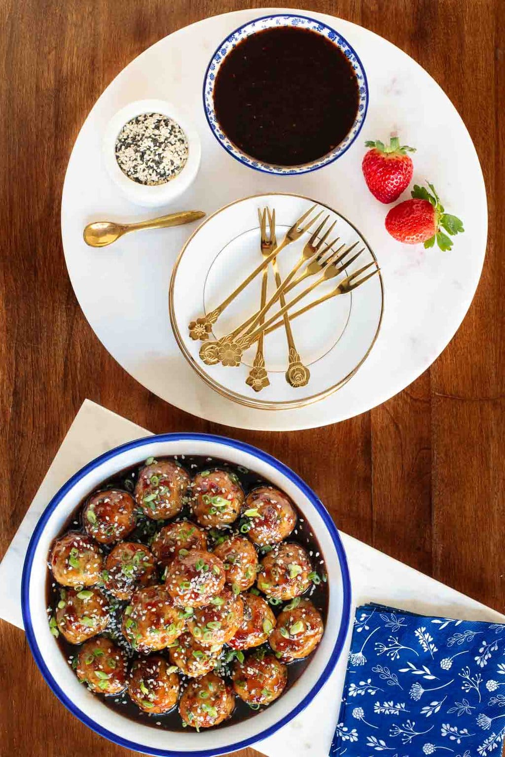 Vertical overhead photo of a bowl of Strawberry Balsamic Glazed Chicken Meatballs on a wood table.