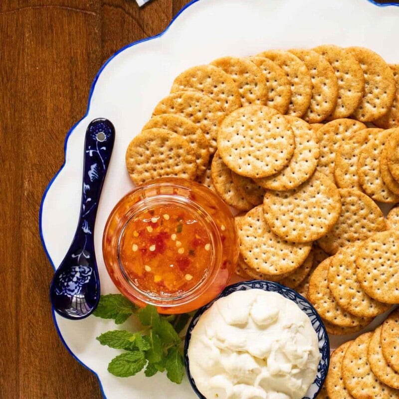 Vertical overhead picture of Mango Jalapeno Pepper Jelly on a cheese plate with crackers