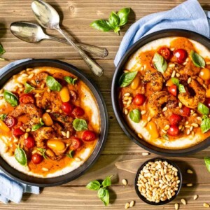 Horizontal overhead photo of two serving bowls of Brown Butter Tomato Shrimp and Grits.