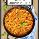 Vertical overhead photo of a cast iron pan of Brown Butter Tomato Shrimp and Grits on a wood table.