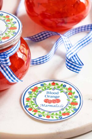 Decorative jars of blood orange marmalade with blue gingham ribbons for gifting or breakfast.