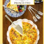 Vertical overhead photo of a Classic Quiche Lorraine with Prosciutto on a wood table with a bowl of fresh fruit.