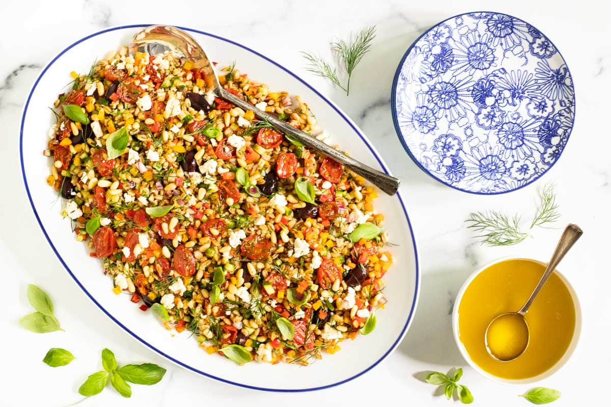 Horizontal overhead photo of a Chopped Mediterranean Farro Salad on a white with blue trimmed serving platter.