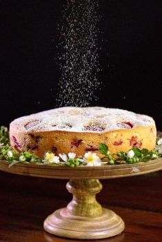 Vertical picture of Fresh Strawberry Cake with powdered sugar on a wooden cake stand