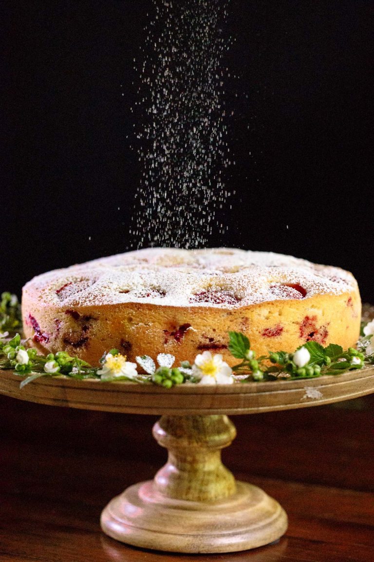 Vertical picture of Fresh Strawberry Cake with powdered sugar on a wooden cake stand