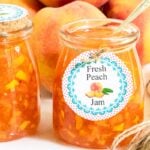 Horizontal closeup photo of a batch of Peach Freezer Jam with custom labels for gift giving.