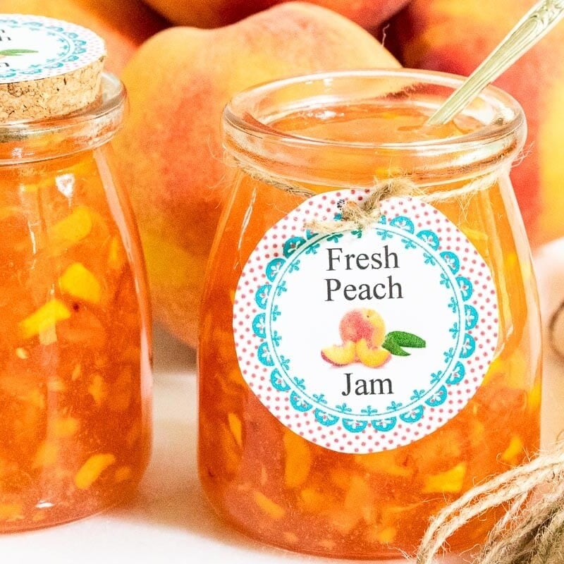 close up of a batch of Peach Freezer Jam with custom labels for gift giving.
