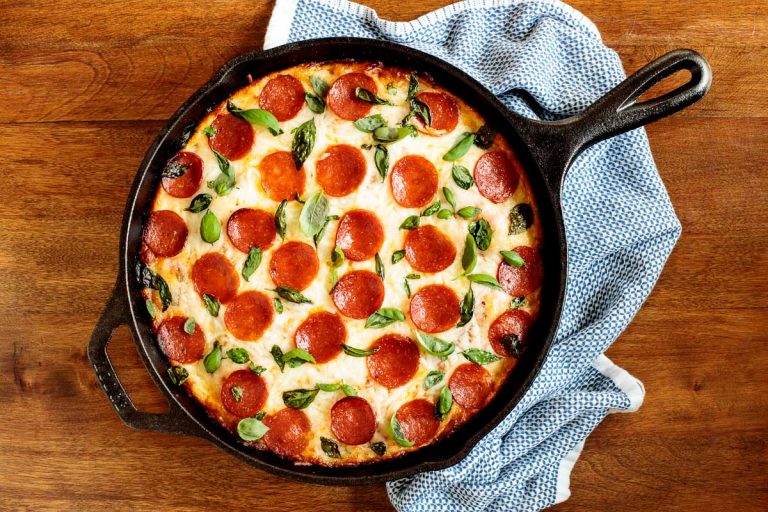 Horizontal overhead photo of an Easy Deep Dish Pepperoni Pizza in a black skillet on a wood table.