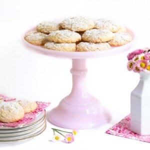 Horizontal photo of a batch of Ridiculously Easy French Almond Cookies on a pink pedestal serving plate.