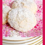 Vertical photo of a plate of French Almond Cookies on pink, white and gold napkins.