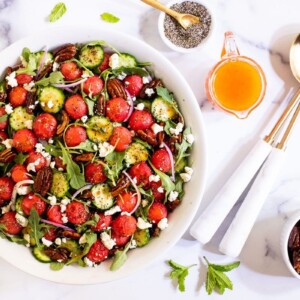 Horizontal overhead photo of a Watermelon Arugula Salad with Pepper Jelly Dressing in a serving bowl on a white marble surface.