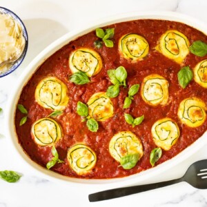 Horizontal overhead photo of a white baking dish of Make-Ahead Italian Zucchini Involtini.