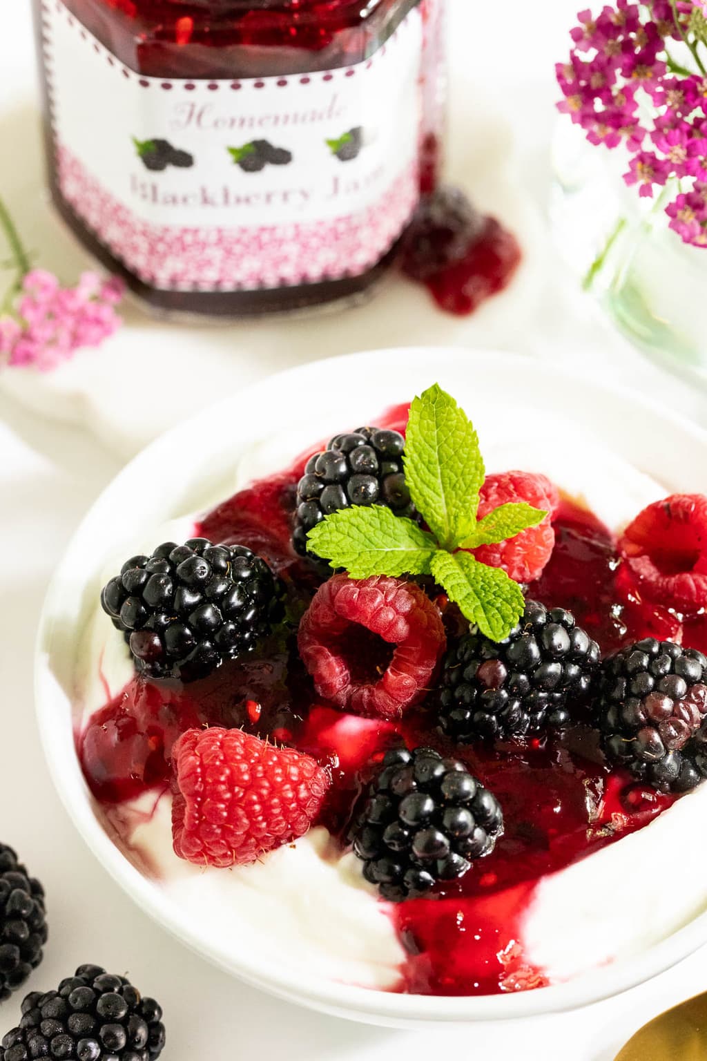 Vertical closeup of a bowl of yogurt with blackberries, raspberries and Easy 30-Minute Blackberry Freezer Jam.