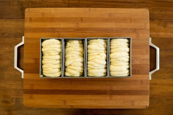 Overhead horizontal process photo of four loaves of No Knead Pull-Apart Brioche Bread dough ready for baking.