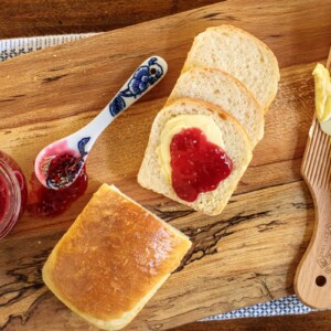 Horizontal overhead photo of a loaf of Overnight No-Knead Brioche Bread with jam and butter spread on the bread.