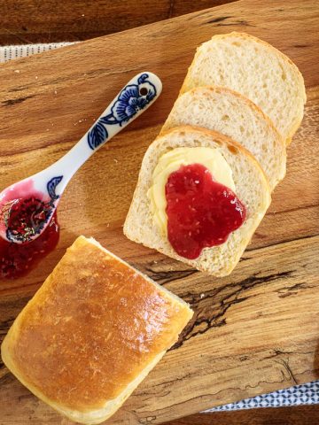 Horizontal overhead photo of a loaf of Overnight No-Knead Brioche Bread with jam and butter spread on the bread.