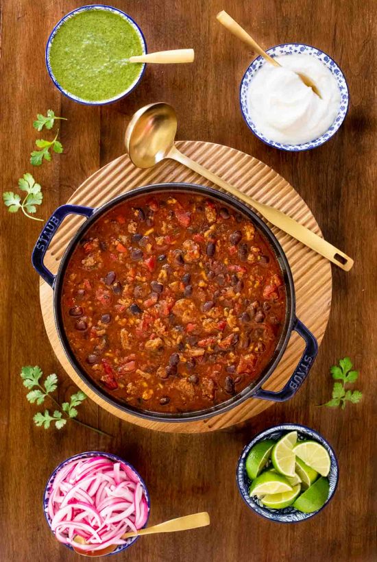 Vertical overhead photo of a pot of Black Bean Turkey Chili on a wood table.