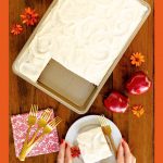 Vertical overhead photo of a Ridiculously Easy Applesauce Sheet Cake on a wood table surrounded by red apples and orange zinnias with a word graphic at the bottom of the photo.
