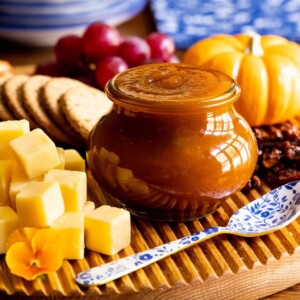 Vertical picture of pumpkin jam in a glass jar on a cheeseboard
