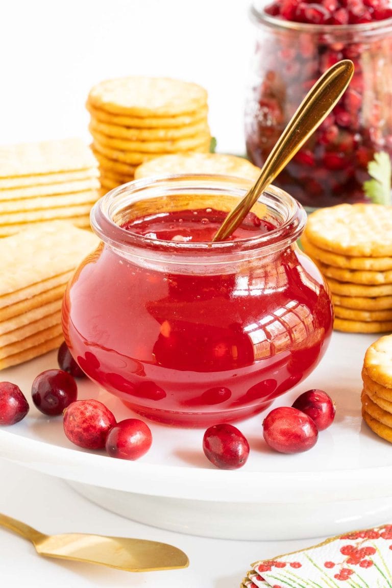 Cranberry Sriracha Pepper Jelly in a small glass jar with cheese and crackers.