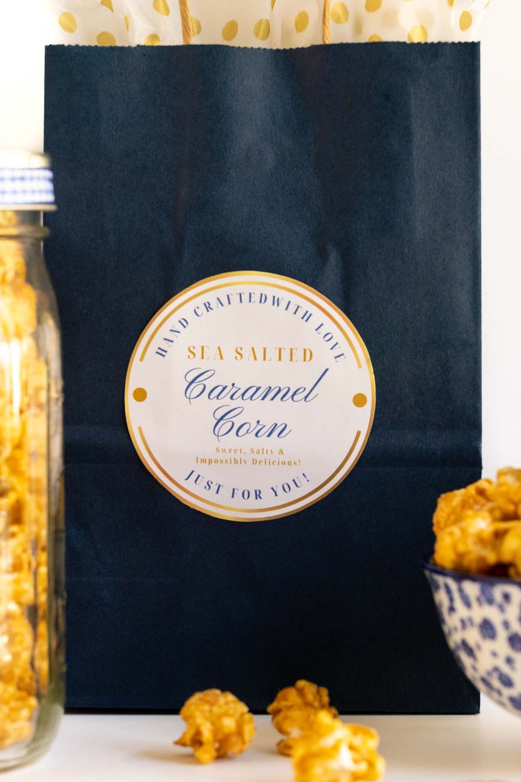Closeup vertical photo of a gift bag with a custom label for Ridiculously Easy Sea Salted Microwave Caramel Corn.